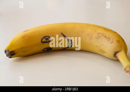 un sorriso viene disegnato su una banana che giace sul tavolo la mattina per la colazione per un bambino Foto Stock