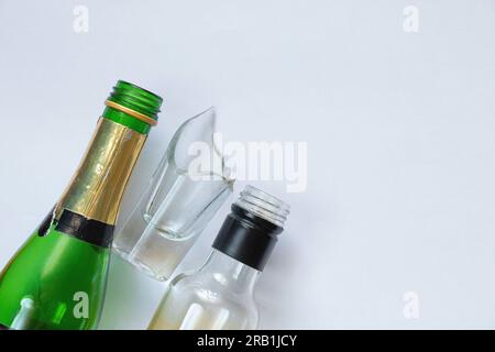 vetro rotto e bottiglia vuota di bevanda alcolica su sfondo bianco, dipendenza da alcol Foto Stock