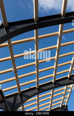 Capannone, costruzione del tetto, processo di costruzione Di Una tettoia in legno da pannelli e trave in acciaio strutturale, non ci sono persone. Cielo blu sullo sfondo. Ingegneria Foto Stock