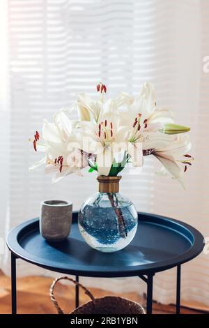 Primo piano del bouquet estivo di fiori di rose messo in vaso trasparente sul tavolo vicino alla finestra. Interni accoglienti e arredamento a casa. Spazio Foto Stock
