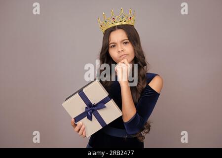 Una seria principessa adolescente in corona. La bambina adolescente si congratula con il giorno delle valentine, regalando una romantica confezione regalo. Presente, saluto e gi Foto Stock