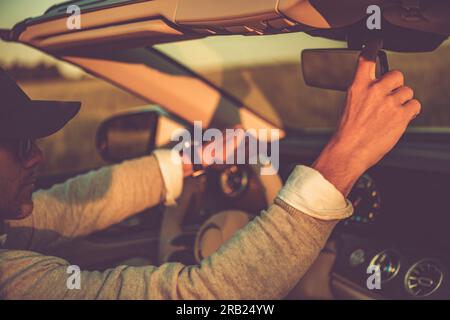 Primo piano dello specchio retrovisore regolabile di un uomo di mezza età ricco e di successo nella sua moderna Luxury Convertible Car. Foto Stock