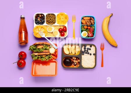 Cestini per il pranzo con diversi piatti gustosi su sfondo lilla Foto Stock