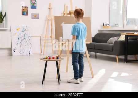 Pittura di un bambino in studio, vista sul retro. Utilizzo del cavalletto  per tenere il quadro Foto stock - Alamy