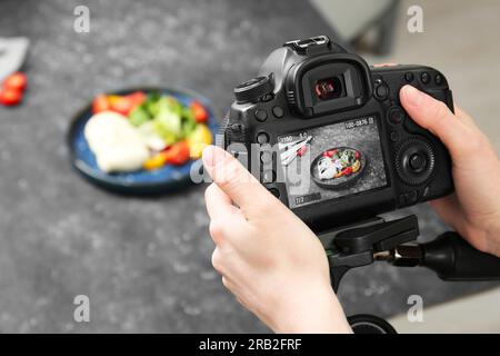 Donna che scatta foto di un'insalata di mozzarella sul tavolo in uno studio fotografico professionale, primo piano. Fotografia del cibo Foto Stock