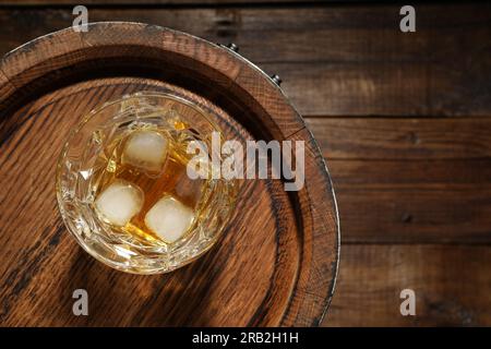 Bicchiere di whisky e barile su sfondo di legno, vista dall'alto. Spazio per il testo Foto Stock