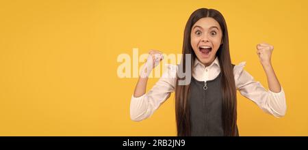 La vincitrice di una ragazza adolescente felice regala un gesto vincente che celebra la vittoria sfondo giallo, vinto. Viso bambino, poster orizzontale, portr. Isolata ragazza adolescente Foto Stock