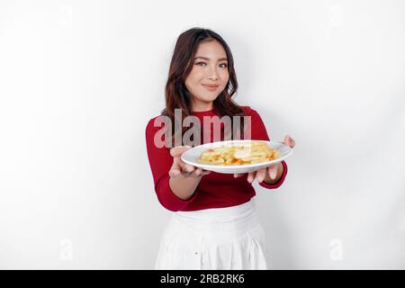 Immagine di una giovane ragazza asiatica sorridente che mangia patatine fritte isolate su sfondo bianco Foto Stock