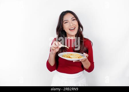 Immagine di una giovane ragazza asiatica sorridente che mangia patatine fritte isolate su sfondo bianco Foto Stock