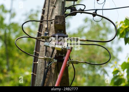 elettricista che utilizza un'asta di bloccaggio per riparare l'interruttore fusibile bassa tensione sul polo di alimentazione elettrica. Foto Stock