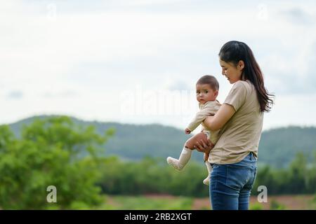 madre felice che tiene il suo bambino nella verde montagna Foto Stock