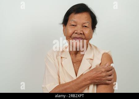 anziana donna anziana felice che mostra cotone sul braccio dopo aver ottenuto un vaccino Foto Stock