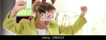 Felice donna d'affari entusiasta con mani sollevate e notebook. Donna celebra il suo successo e guarda lo schermo del computer. Foto Stock