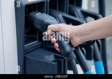 Ricarica dell'energia pulita del veicolo elettrico per guidare il futuro. supporto manuale della stazione di ricarica. Foto Stock