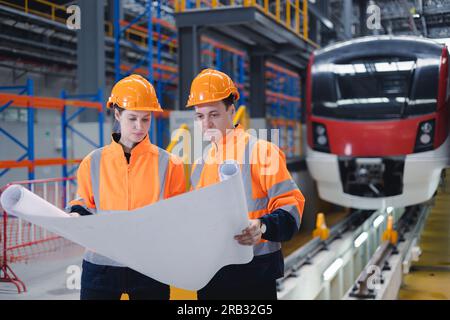 Ingegnere del treno elettrico meccanico del personale addetto al team che cerca il piano di sistema per il programma di manutenzione controllare il servizio di funzionamento del treno nell'officina della fabbrica di treni. Foto Stock