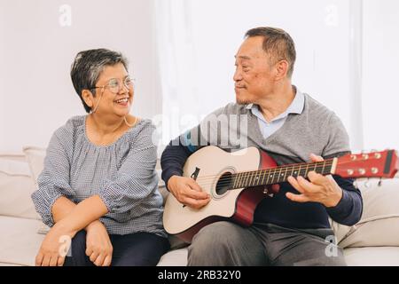 Anziani coppia amante vacanza attività casa vecchio che suona la chitarra musica fanno felice moglie anziana sorriso Foto Stock