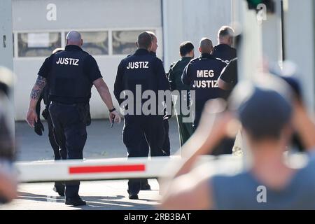 Itzehoe, Germania. 7 luglio 2023. I funzionari giudiziari portano l'imputato, Che è assicurato con le manette e le caviglie, al China Logistic Center per l'inizio del processo, dove il processo per omicidio e tentato omicidio nel caso dell'attacco di coltello sul treno vicino a Brokstedtvor inizia venerdì presso il tribunale regionale di Itzehoe. Credito: Christian Charisius/dpa/Alamy Live News Foto Stock