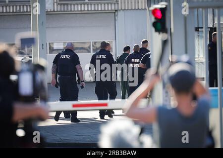 Itzehoe, Germania. 7 luglio 2023. I funzionari giudiziari portano l'imputato, Che è assicurato con le manette e le caviglie, al China Logistic Center per l'inizio del processo, dove il processo per omicidio e tentato omicidio nel caso dell'attacco di coltello sul treno vicino a Brokstedtvor inizia venerdì presso il tribunale regionale di Itzehoe. Credito: Christian Charisius/dpa/Alamy Live News Foto Stock