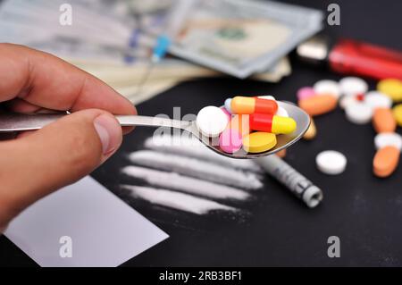 Siringa del farmaco e pillole sul cucchiaio in mano Foto Stock