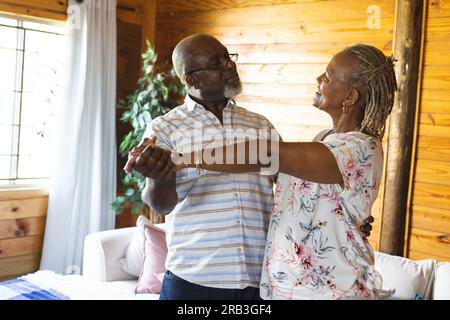 Felice coppia afro-americana anziana che balla in salotto. Stile di vita senior, relax e pensionamento, inalterato. Foto Stock
