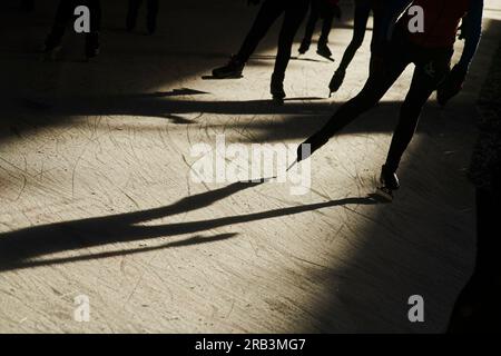 Silhouette di folle di persone che pattinano sul ghiaccio in un luminoso sole invernale Foto Stock