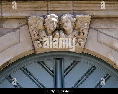 Edificio in pietra con porta e architrave blu decorato con due figure d'angelo. Foto Stock