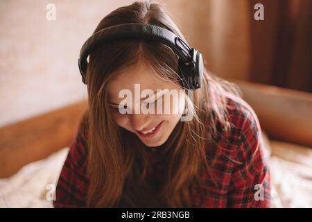 Felice adolescente che ascolta musica con le cuffie wireless Foto Stock