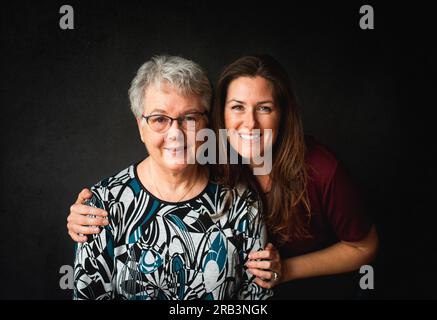 Ritratto di una madre e di una figlia adulta su sfondo nero. Foto Stock