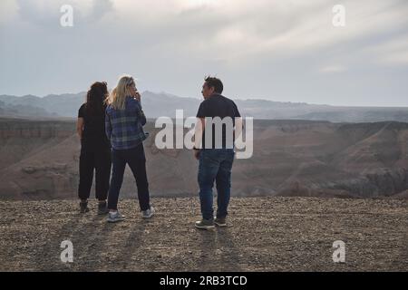 Tre persone che guardano al Grand Canyon da un punto di vista, ventoso Foto Stock