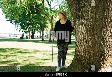 pensionato che si prende una pausa dal camminare con un bastone fuori Foto Stock