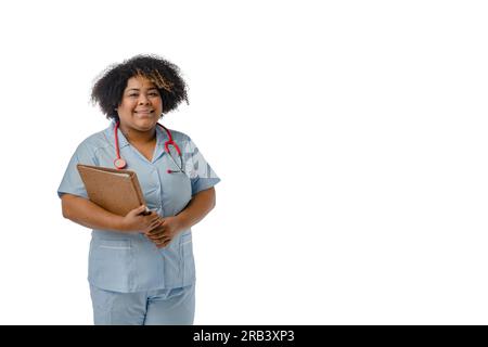 Medico afro-latina di etnia venezuelana in uniforme blu con uno stetoscopio rosso sul collo, sorridendo guardando la macchina fotografica e tenendo in mano un Foto Stock