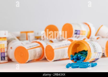 pillole blu che escono dal flacone di pillola da prescrizione con etichetta su sfondo bianco Foto Stock