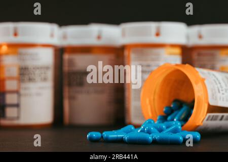 pillole blu che escono dal flacone di pillola da prescrizione su sfondo nero Foto Stock