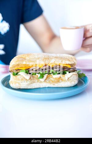 Arrosto di manzo con ciabatta di prima scelta tagliata alla julienne servito in una caffetteria con caffè espresso caldo. Foto Stock