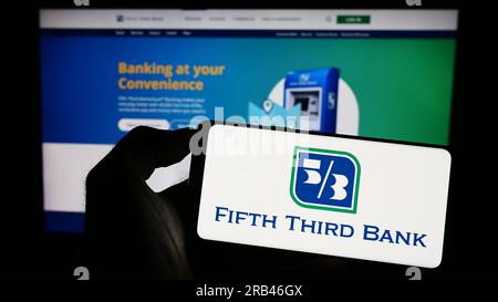 Persona che possiede il cellulare con il logo della società finanziaria Fifth Third Bancorp (Banca 53) sullo schermo davanti alla pagina web. Concentrarsi sul display del telefono. Foto Stock