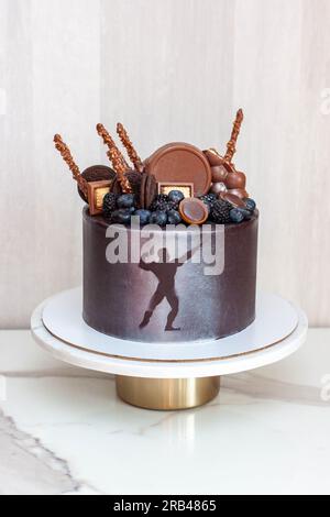 L'idea di una torta di compleanno per un bodybuilder, un atleta, un sollevatore elettrico o un maratoneta. Torta decorata con frutti di bosco freschi e cioccolato Foto Stock