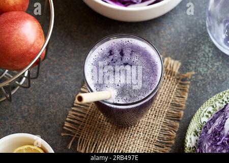 Un bicchiere di succo di cavolo viola con mele fresche e paglia di bambù - concetto a zero sprechi Foto Stock