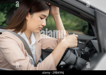 Triste e stanco giovane lavoratrice asiatica seduta in macchina pensando ai suoi problemi al lavoro Foto Stock