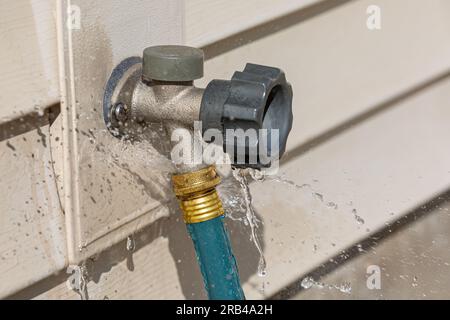 Perdite d'acqua dal tubo da giardino sul raccordo esterno. Rifiuti idrici, conservazione e riparazione domestica. Foto Stock