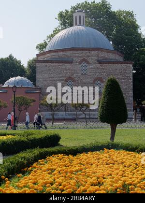 Hurrem Sultan Hamami (bagno turco) esterno mentre i visitatori camminano accanto ai vicini giardini, al quartiere di Sultanahmet, a Istanbul, in Turchia Foto Stock