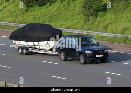 2011 Land Rover Range Rover Vogue TDV8 Un TDV8 Auto Black Car SUV Diesel da 4367 cc che traina una grande barca bianca su un rimorchio A doppio assale; viaggia a velocità sostenuta sull'autostrada M6 a Greater Manchester, Regno Unito Foto Stock