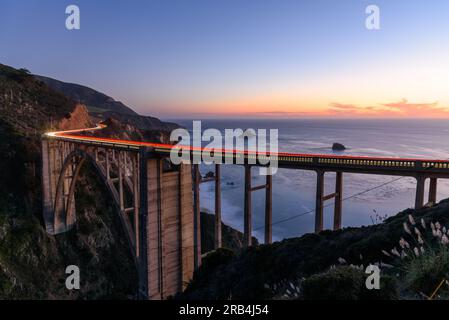 Percorsi leggeri lasciati passando accanto ai veicoli sul ponte Bixby Creek sulla costa della California centrale al crepuscolo in autunno Foto Stock