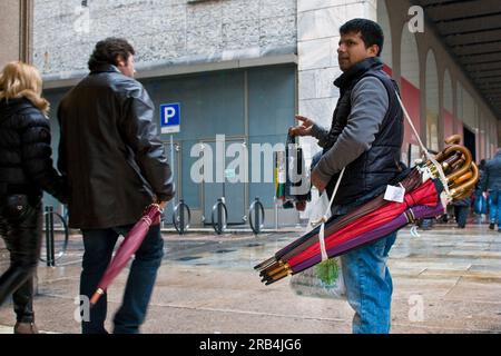 Immigrato bengalese che vende ombrelli. Milano. Italia Foto Stock