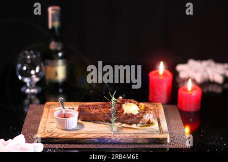 Costata di manzo sul nuovo anno di tabella. Bistecca costola arrosto occhio su una tavola di legno con salsa di pomodoro e il sale. Bistecca sul piatto di legno. Foto Stock