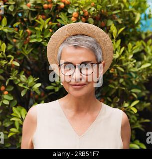 Ritratto di una donna anziana elegante con occhiali da vista e cappello di paglia Foto Stock