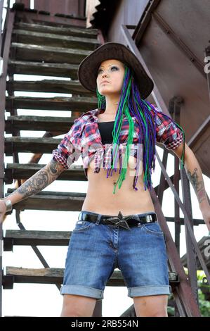 giovane donna tatuata ed elegante con dreadlock in stile contadino Foto Stock