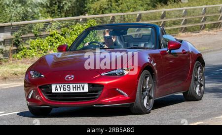 Milton Keynes, Regno Unito - 7 luglio 2023: 2019 auto MAZDA MX-5 rossa con tetto aperto che viaggia su una strada del Regno Unito in una giornata di sole Foto Stock