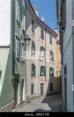 Paesaggio urbano con pittoreschi e colorati edifici storici sulla strada curva, girato alla luce brillante a Muggia, Trieste, Friuli, Italia Foto Stock