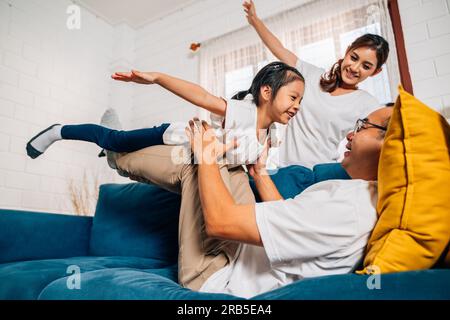 Padre madre e figlia fanno esercizio fisico nel soggiorno di casa Foto Stock