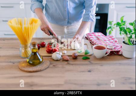 Giovane donna che prepara la pasta al pomodoro nella cucina di casa Foto Stock